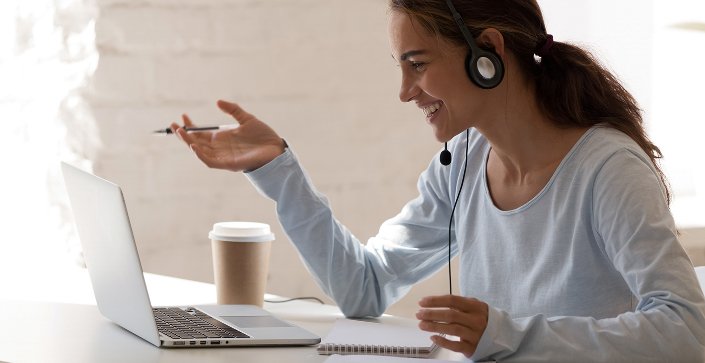 Smiling millennial lady freelancer wearing headset, communicating with client.